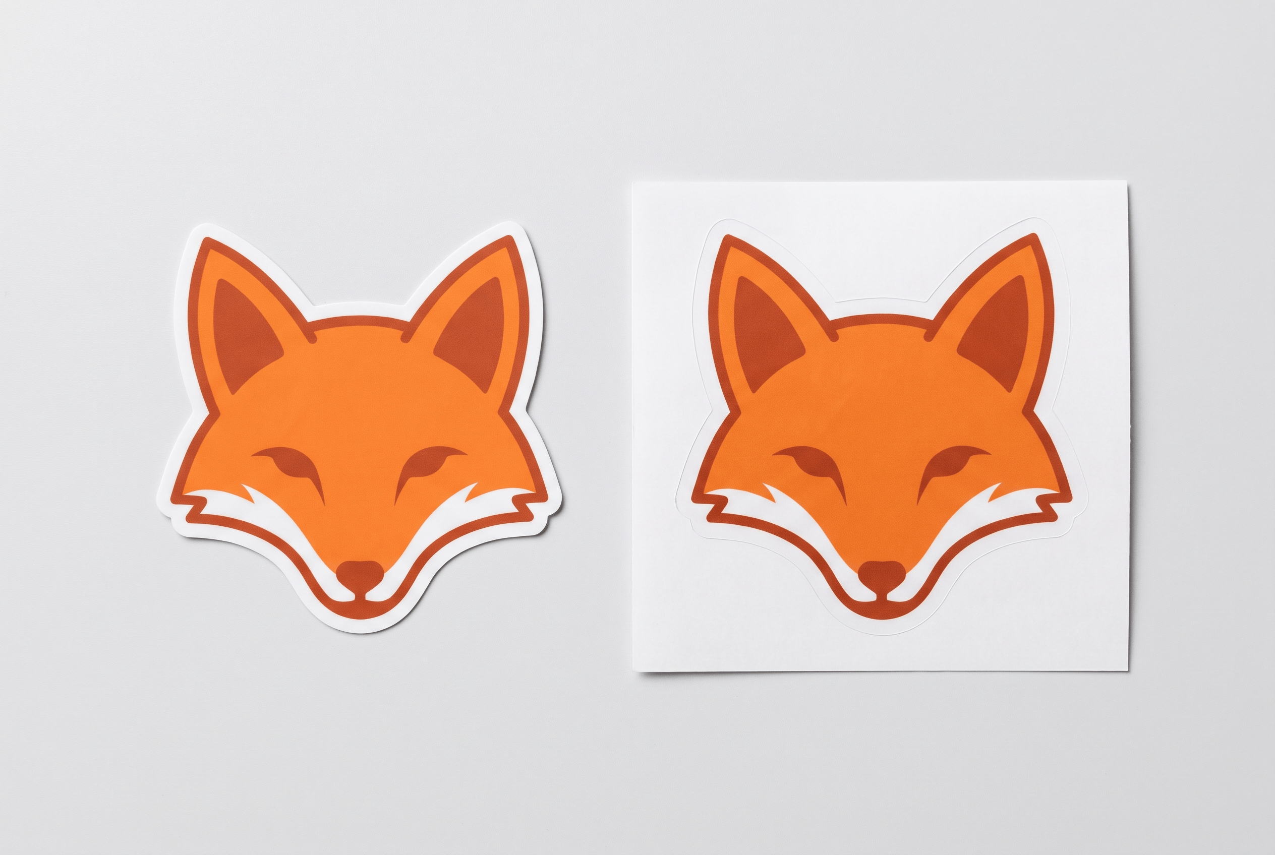 A die-cut sticker cut to shape next to a kiss-cut sticker with a border on backing